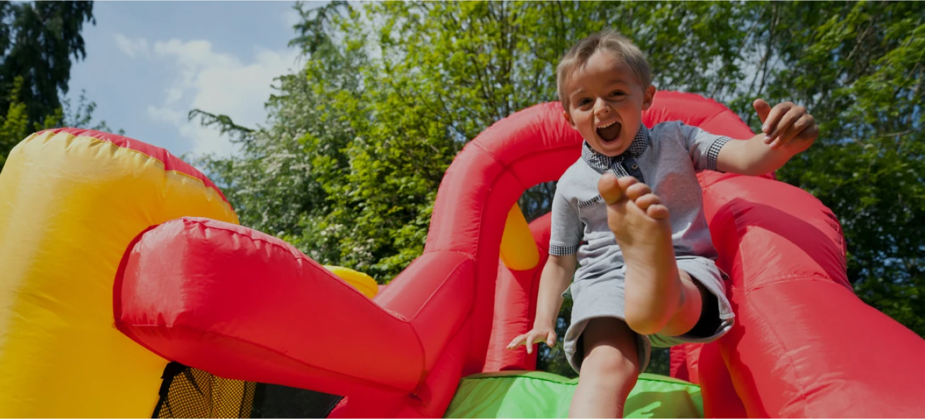 Child sliding on an inflatable water slide rental in a backyard
